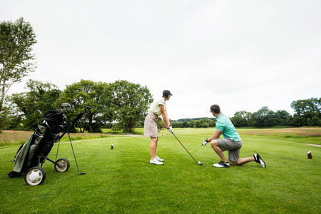 Male instructor assisting woman in learning golf at golf courseの写真素材