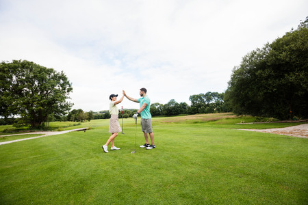 Couple giving high five to each other in golf courseの写真素材