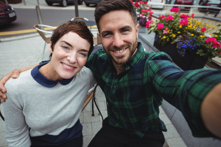 Portrait of couple posing for selfie in cafeteriaの写真素材
