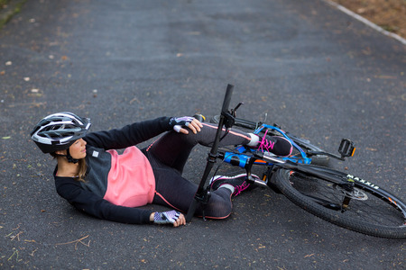 Female biker fallen from his mountain bike on the roadの写真素材