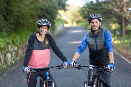 Biker couple with mountain bike on the countryside roadの写真素材