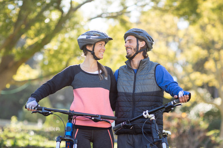 Biker couple standing with mountain bike in countrysideの写真素材