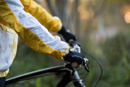 Mid-section of male biker with mountain bike in countrysideの写真素材