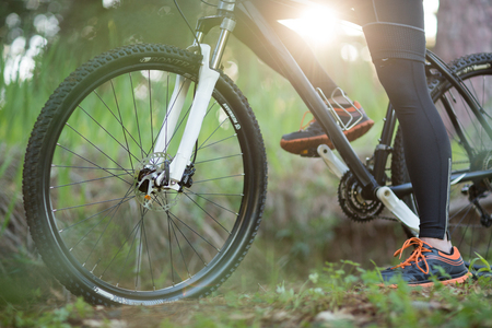Low section of male biker with mountain bike in countrysideの写真素材