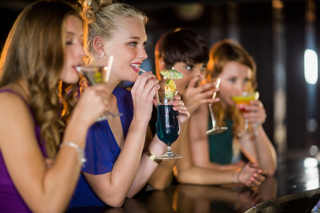 Smiling friends having glass of cocktail in barの写真素材
