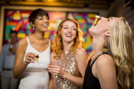 Woman balancing a shot glass on her mouth in barの写真素材