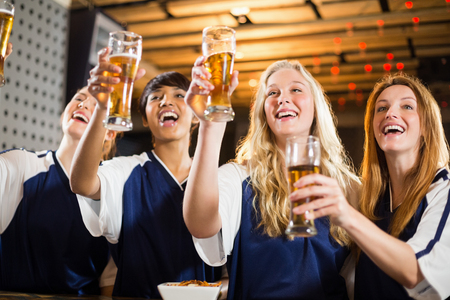 Group of smiling friends holding glass of beer in party at barの写真素材