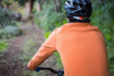 Male mountain biker riding bicycle in the forest on a sunny dayの写真素材