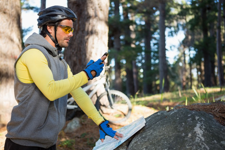 Mountain biker using mobile phone in the forestの写真素材