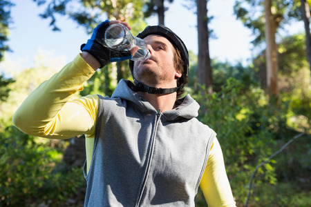 Mountain biker drinking water in the forestの写真素材