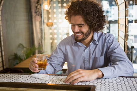 Man having glass of whisky in bar counter at barの写真素材