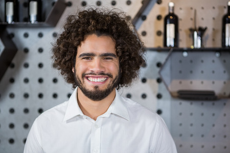 Portrait of smiling bartender standing in bar counterの写真素材