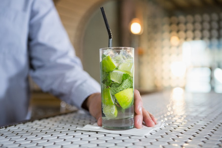 Close-up of man holding glass of gin in barの写真素材