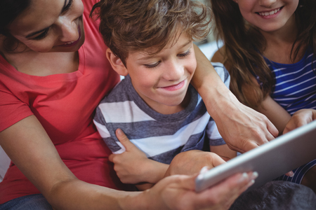 Close-up of mother and kids using digital tablet together at homeの写真素材
