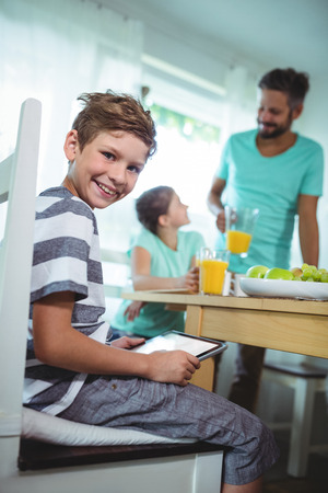 Portrait of boy using digital tablet with breakfast on table at homeの写真素材