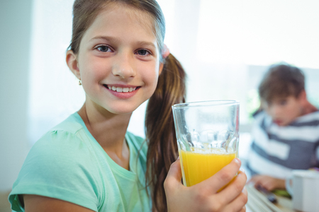 Smiling girl having orange juice at homeの写真素材
