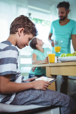 Portrait of boy using digital tablet with breakfast on table at homeの写真素材
