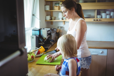 Mother and daughter chopping vegetable in the kitchen at homeの写真素材
