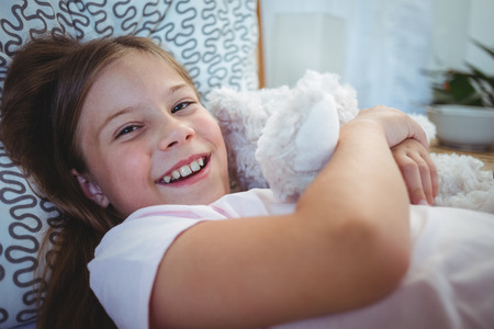 Portrait of happy girl lying with a teddy bear at homeの写真素材