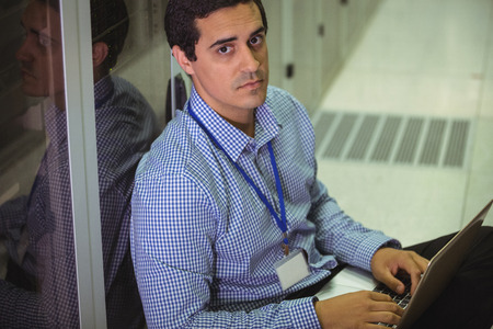 Portrait of technician using laptop in server room