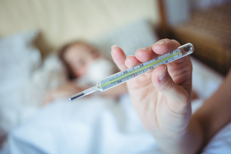 Mother holding a thermometer at homeの写真素材