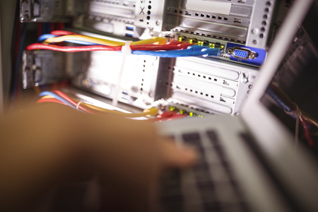 Technician working on laptop in server room