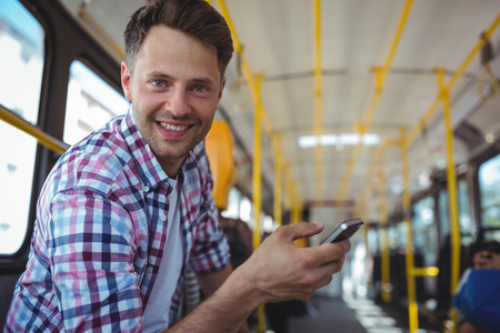 Portrait of handsome man using mobile phone in busの写真素材