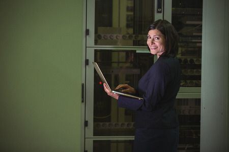Portrait of technician using laptop while analyzing server in server roomの写真素材