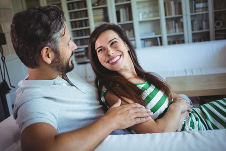 Happy couple lying on sofa in living room at homeの写真素材