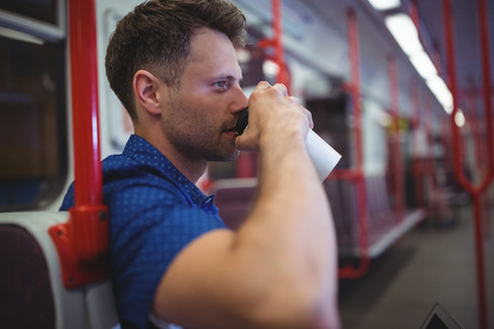 Handsome man drinking coffee in trainの写真素材
