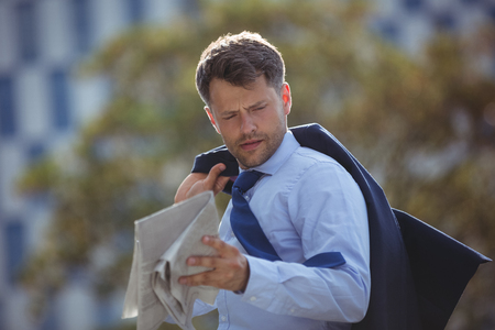 Handsome businessman reading newspaper near office buildingの写真素材