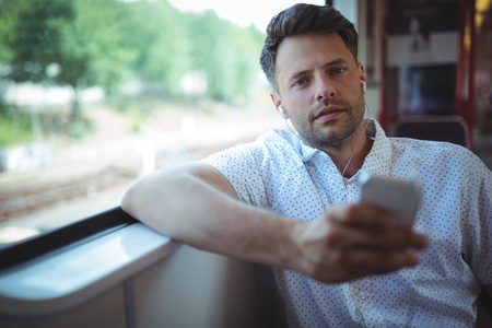Handsome man listening music on mobile phone in trainの写真素材