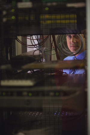 Technician checking cables in a rack mounted server in server room