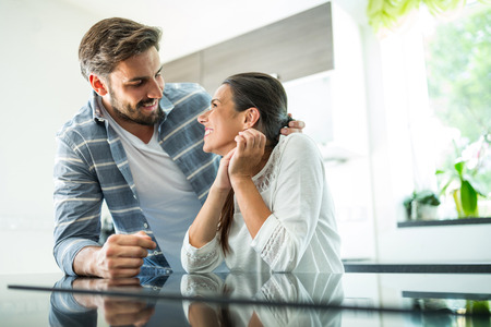 Romantic couple looking at each other in kitchenの写真素材