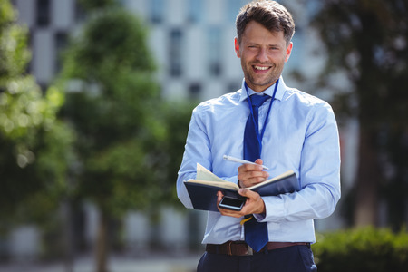 Portrait of handsome businessman writing in dairyの写真素材