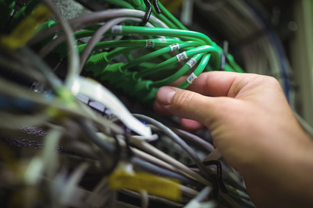 Technician plugging patch cable in a rack mounted server in server roomの写真素材