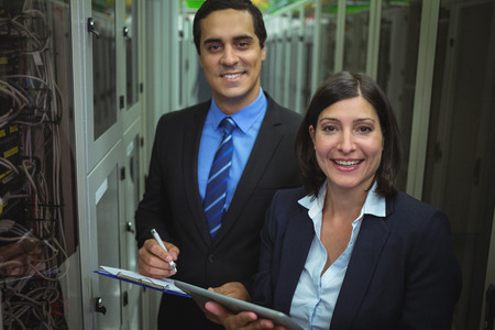 Portrait of technicians analyzing server in server room