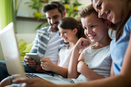 Happy family using laptop and digital tablet in the living room at home