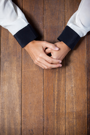 Praying hands of woman on wooden deskの写真素材