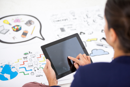 Businesswoman using digital tablet while working on icon chartsの写真素材