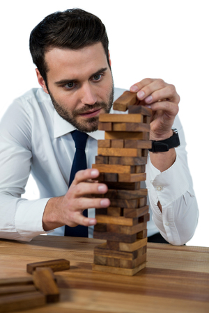 Businessman placing wooden block on a towerÂ against white backgroundの写真素材