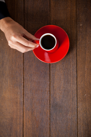 Woman holding a cup of coffee on wooden tableの写真素材