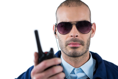 Handsome security officer talking on walkie-talkie against white backgroundの写真素材