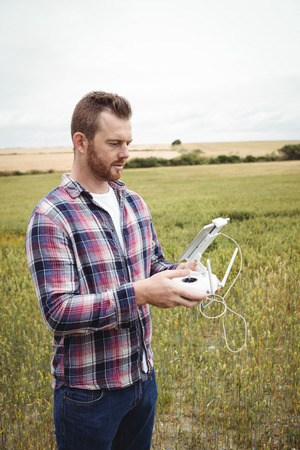 Farmer using agricultural device while examining in field on a sunny day