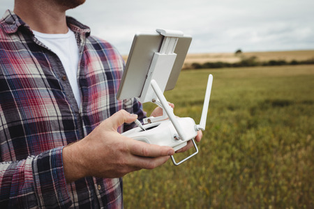 Farmer using agricultural device while examining in field on a sunny dayの写真素材