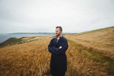 Farmer standing with arms crossed in the field on a sunny dayの写真素材