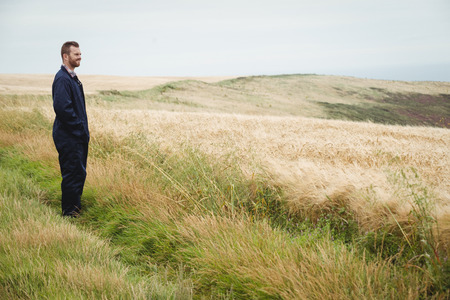 Thoughtful farmer standing in field on a sunny dayの写真素材
