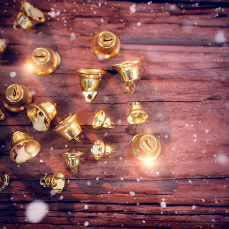Snow falling against golden bells on wooden plankの写真素材
