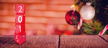 Composite image of changing year stack of cubes against bauble decorations on christmas tree