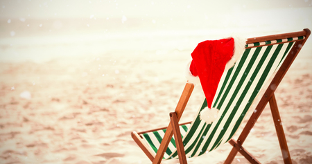 Snow falling against santa hat kept on empty beach chairの写真素材